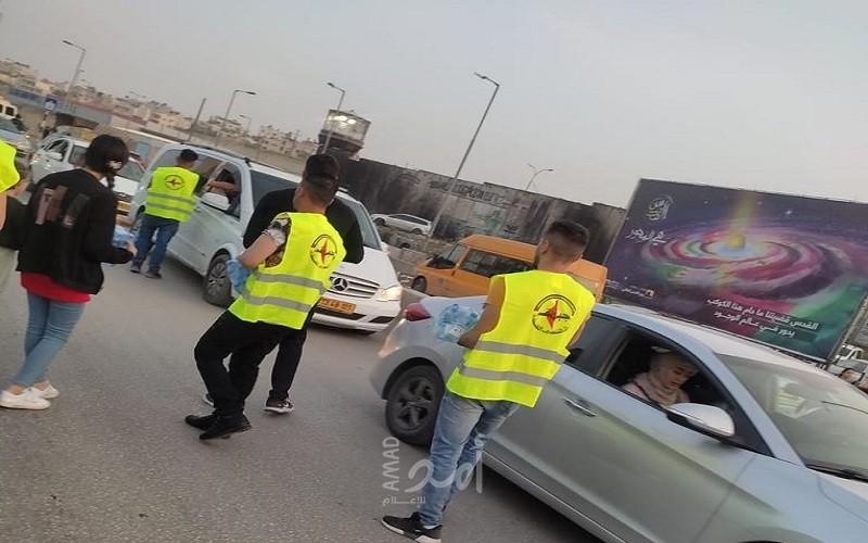متطوعو النضال الشعبي يوزعون الماء والتمر على المواطنين على حاجز قلنديا
