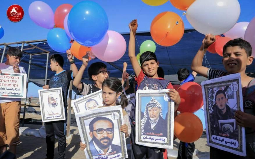 أطفال يطلقون بالونات تحمل صور شخصيات فلسطينية قرب السياج الفاصل شرق قطاع غزة